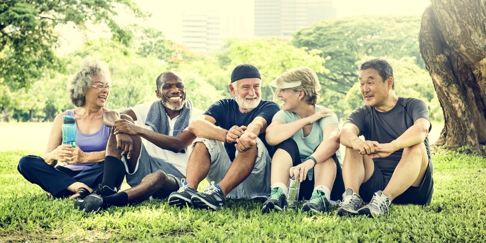 Diverse group of senior sitting in park after exercise