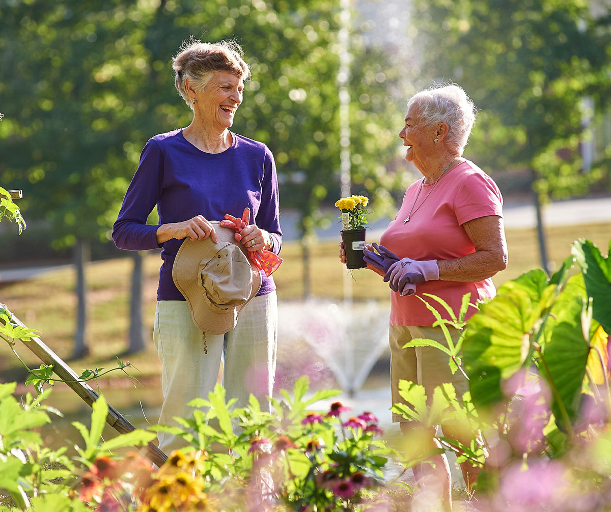 Two senior women pause from gardening to talk