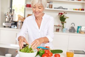 elderly senior woman cooking healthy salad for diet in kitchen