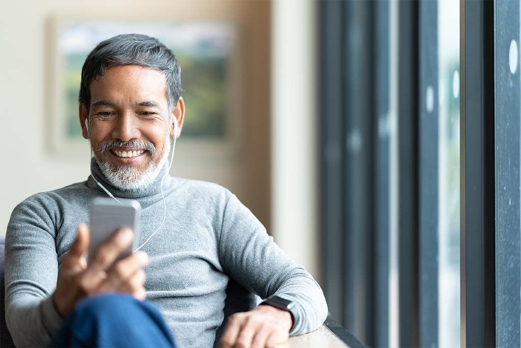 Senior man uses phone to listen to top podcasts 