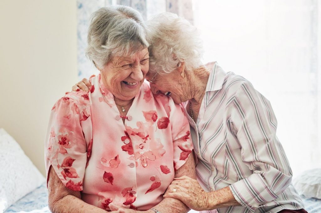 Two senior women having a hug and laugh.