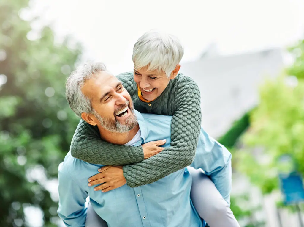 senior man holding senior woman on his back