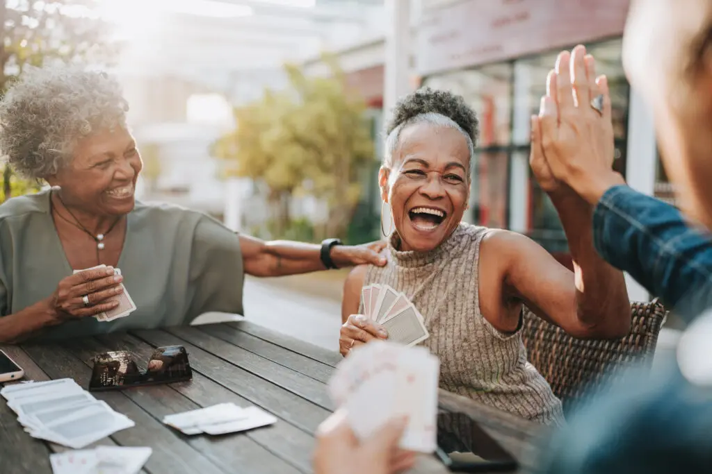 Senior woman high fiving other friends and playing cards