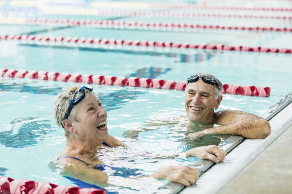 Senior couple treading water at end of pool lane