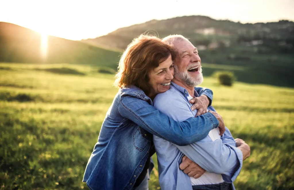 young independent living couple laughing in a field near Rolling Green Village, a senior living community in Greenville, SC.