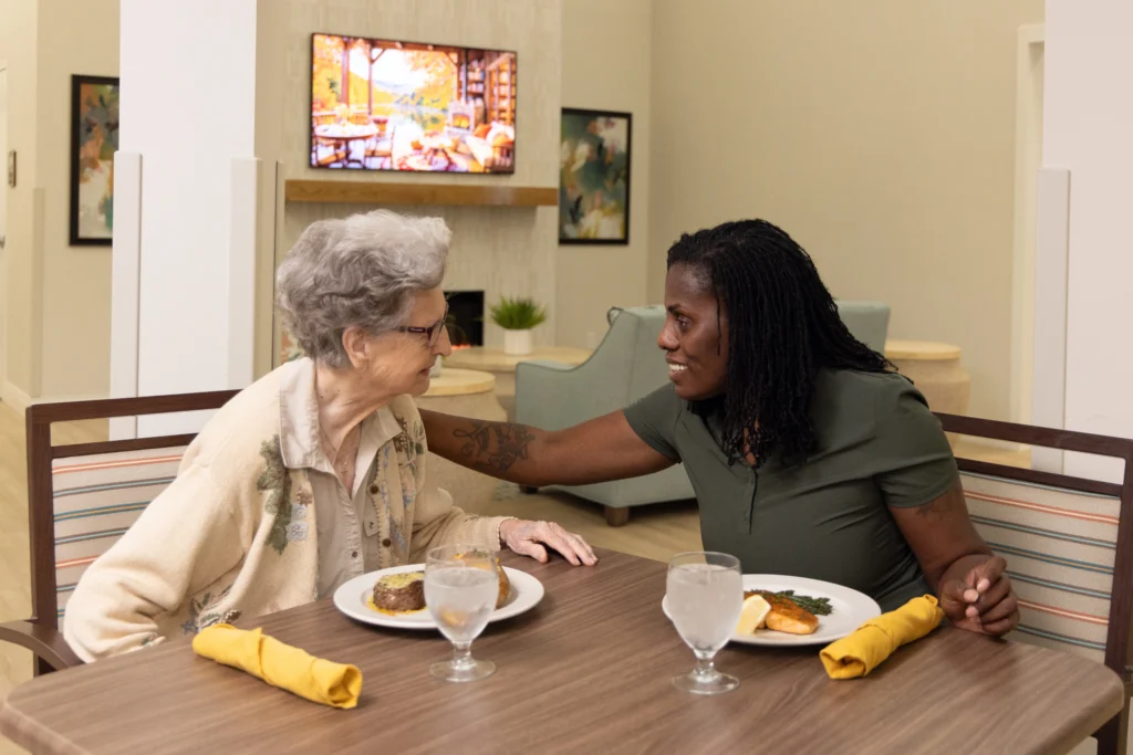 senior woman and staff member dining at Rolling Green Village in a unique memory care design.