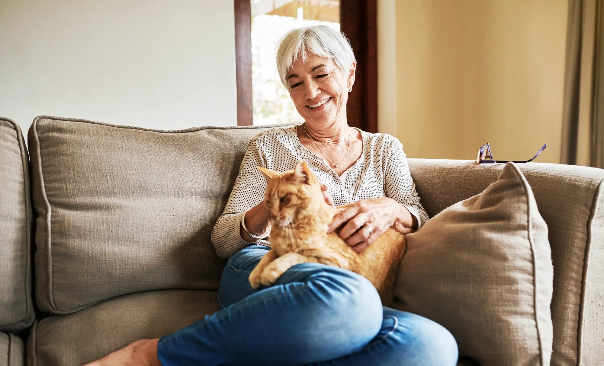 Happy senior woman sitting alone and petting her cat during in her home at Rolling Green Village in Greenville, SC.