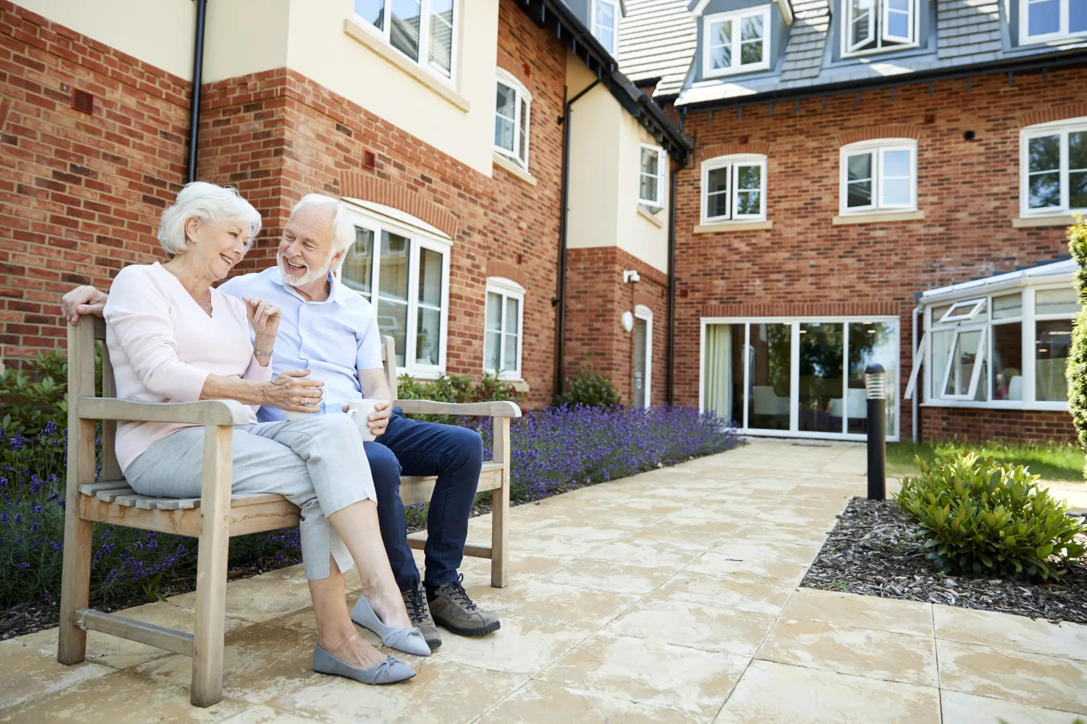A senior couple talking and smiling on a bench while talking about the benefits of for-profit vs non-profit senior living in Greenville, SC.